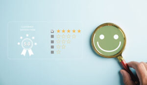 Magnifying glass held by hand selects happy smiley face icon - CX concept